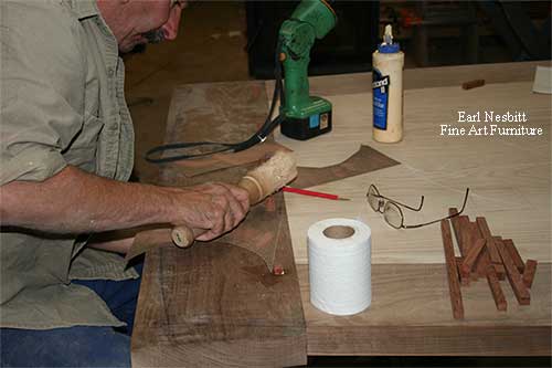 Earl pounds pegs into breadboard ends of custom made dining table